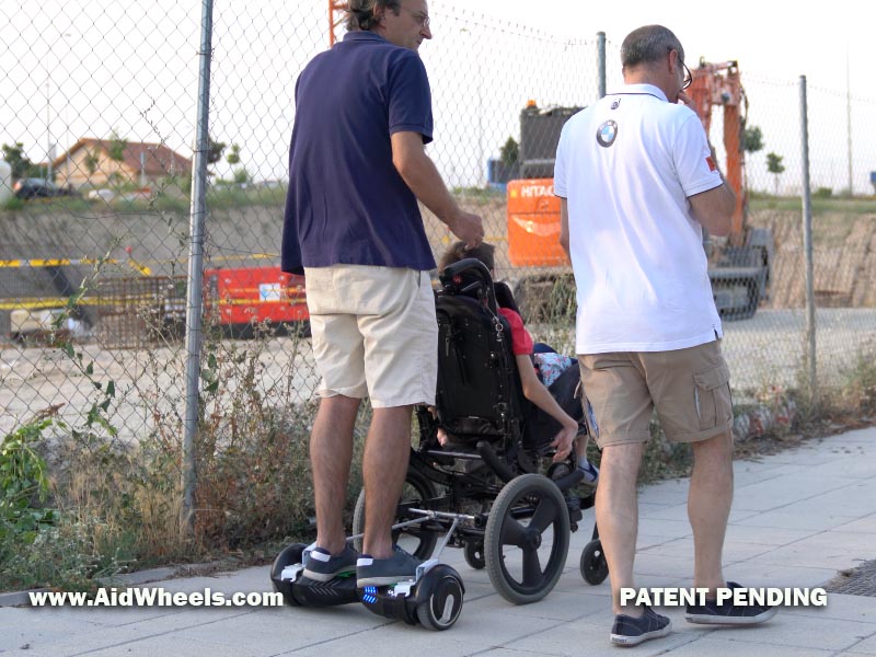 silla de ruedas paseando con un hoverboard empujando